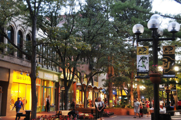 A pedestrian mall with trees and shops alongside
