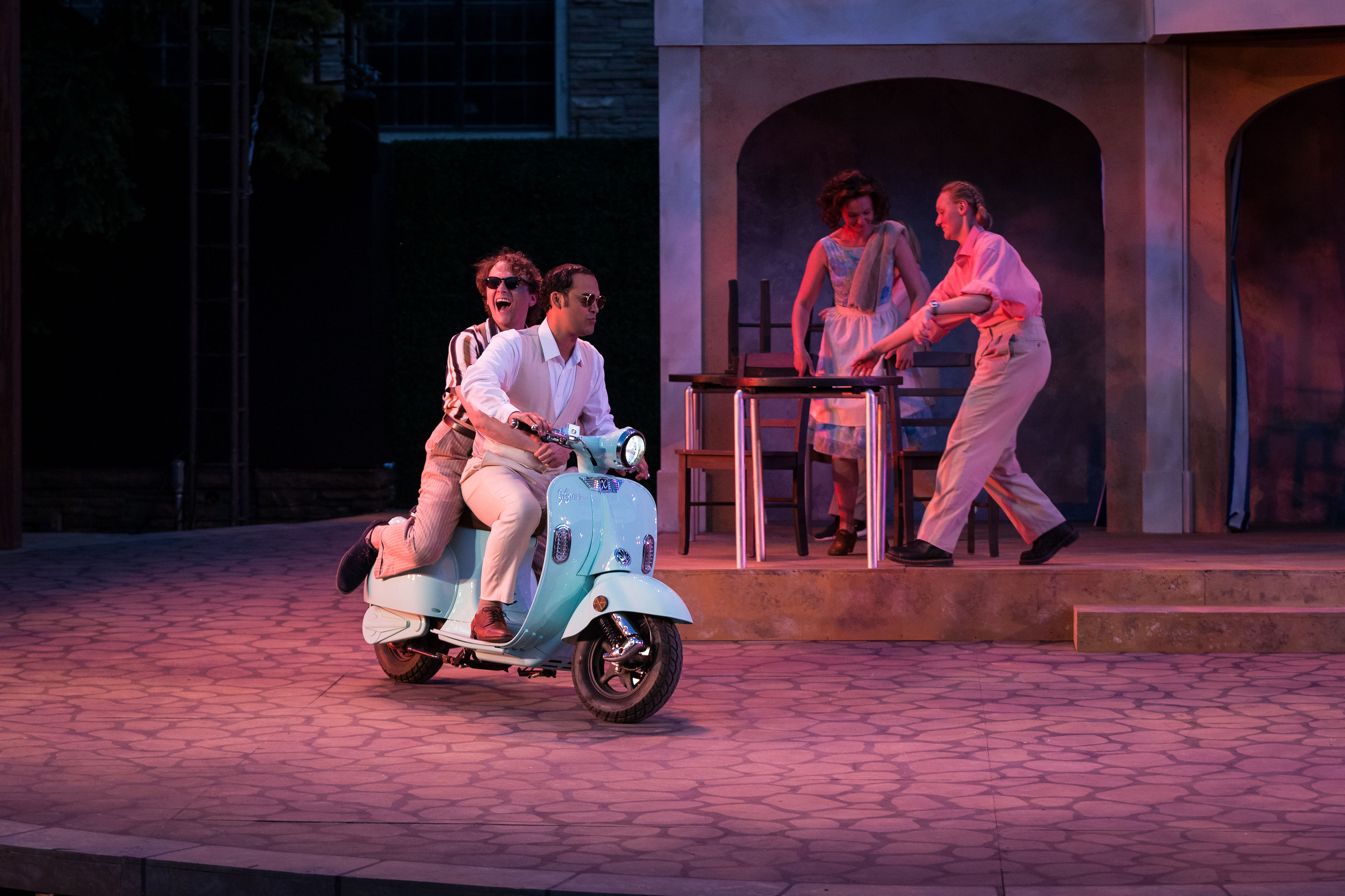 Two men on a moped on stage